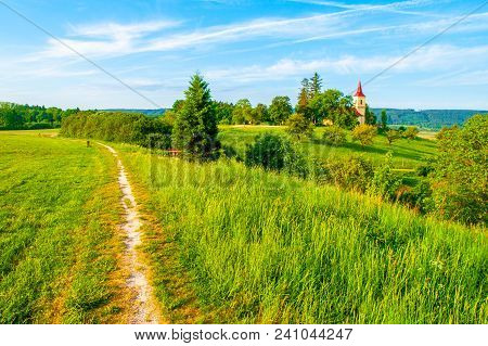 Small Church In The Middle Of Lush Green Spring Landscape On Sunny Day. St. Peter And Pauls Church A