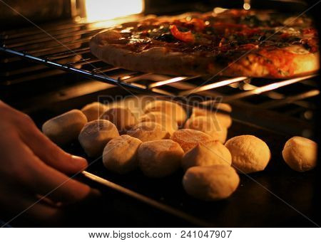 Pizza And Dough Balls Being Placed Into An Oven