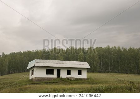Lonely White Forgotten Building On The Green Mountain. Deep Dark Grey Sky With A Lot Of Clouds. Fore