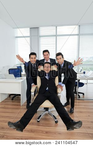 Group Portrait Of Smiling Asian Managers Wearing Classical Suits Posing For Photography While Pushin