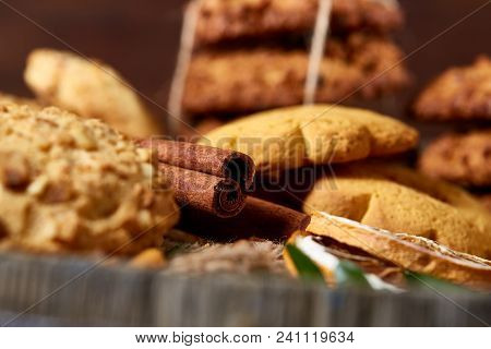 Conceptual Composition With Assortment Of Cookies, Cinnamon Sticks Bunch And Dried Oranges On A Wood