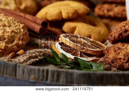 Conceptual Composition With Assortment Of Cookies, Cinnamon Sticks Bunch And Dried Oranges On A Wood