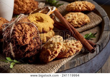 Conceptual Composition With Assortment Of Cookies, Cinnamon Sticks Bunch And Dried Oranges With Burl