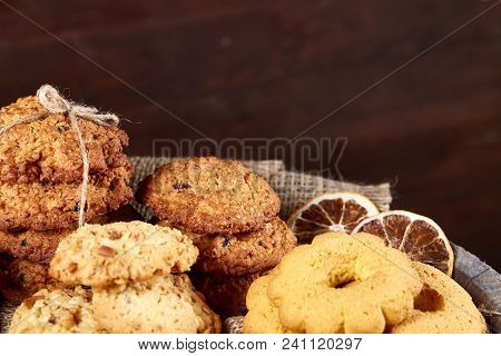 Conceptual Composition With Assortment Of Cookies, Cinnamon Sticks Bunch And Dried Oranges On A Wood