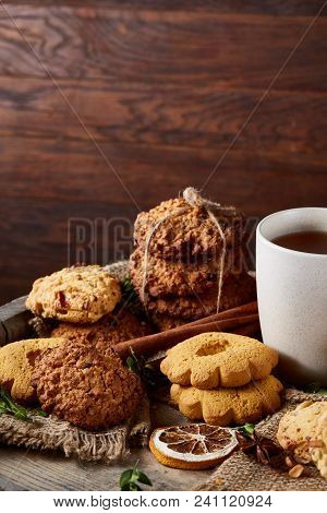 Conceptual Festive Composition With A Cup Of Hot Tea, Large Set Of Cookies, Cinnamon Sticks Bunch An