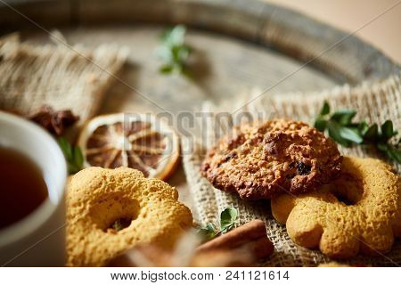 Conceptual Composition With Assortment Of Cookies, Cinnamon Sticks Bunch And Dried Oranges On Burlap