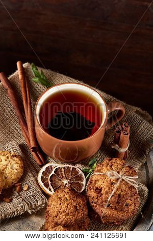 Conceptual Festive Composition With A Cup Of Hot Tea, A Large Set Of Cookies, Cinnamon Sticks Bunch 
