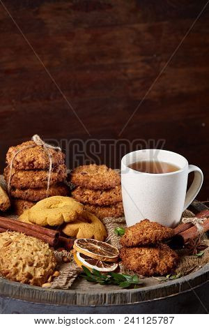 Conceptual Festive Composition With A Cup Of Hot Tea, A Large Set Of Cookies, Cinnamon Sticks Bunch 