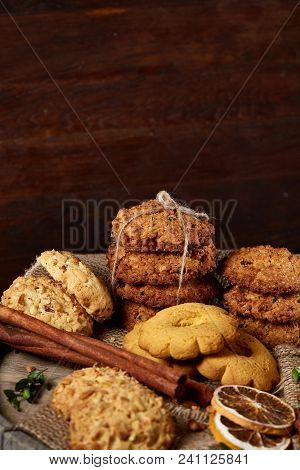 Conceptual Composition With Assortment Of Cookies, Cinnamon Sticks Bunch And Dried Oranges On A Wood
