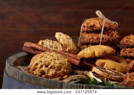 Conceptual Composition With Assortment Of Cookies, Cinnamon Sticks Bunch And Dried Oranges On A Wood
