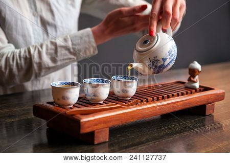 Cropped shot of woman pouring tea in traditional chinese teaware.