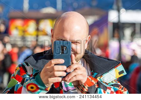 Bold Man In A Bright Jacket With A In The Town , Takes Pictures Of The Landscape On The Phone