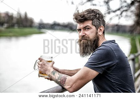 Side View Bearded Man Engoying Big Mug Of Beer On Warm Evening. Brutal Man With Messy Hairstyle And 