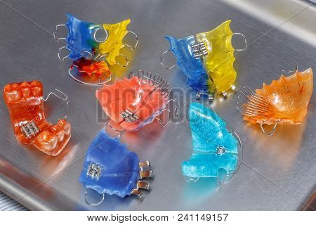 Many Colorful Dental Braces Or Retainers For Teeth On Metall Background, Closeup