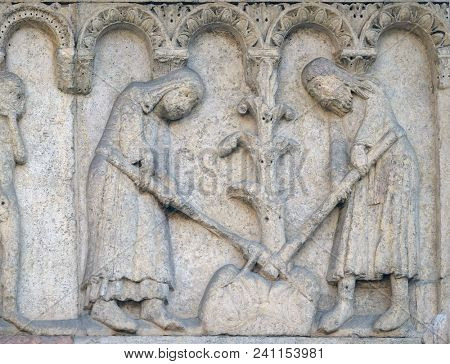 MODENA, ITALY - JUNE 04: Adam and Eve hoe the earth relief by Wiligelmo, Modena Cathedral, Italy on June 04, 2017.