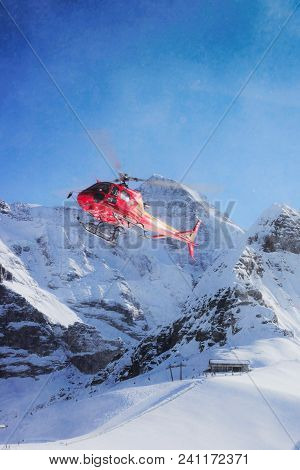 Maennlichen, Switzerland - December 31, 2013: Red Helicopter Flying Near Swiss Alpine Mountain Maenn