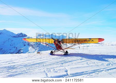 Maennlichen, Switzerland - December 31, 2013: Yellow Airplane At Mountain Alps Peaks In Maennlichen 