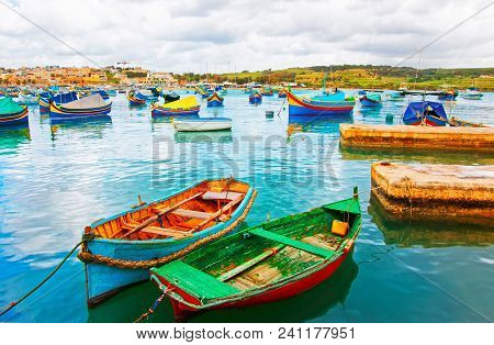 Luzzu Colorful Boats At Marsaxlokk Port At The Bay Of The Mediterranean Sea, Malta Island