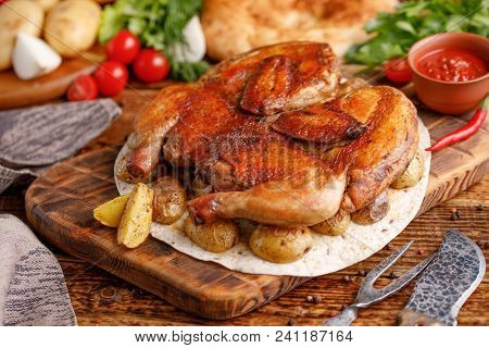 Fried Chicken With Garnish Of Baked Young Potatoes. Still Life On A Wooden Background With Textiles