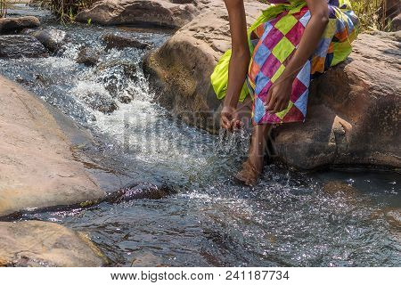 Woman In African Outfit On The Verge Of Fluent River. Interacting With Water. Angola.