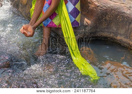 Woman In African Outfit On The Verge Of Fluent River. Interacting With Water. Angola.