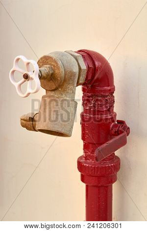 Red Old Fireplug With White Valve Against Of A Wall Background.