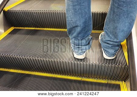 Escalator In The Subway Station With The Man Legs On Sport Shoes And Warm Light