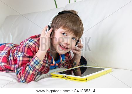 Little Boy In Headphones Laying On Bed Play The Tablet