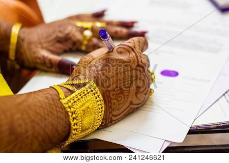 A Newly Married Indian Bengali Wife With Golden Ornament And Blacelet Signing Marriage Registration