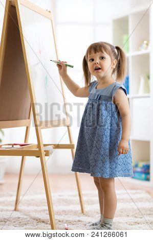 Child Girl Drawing On A White Board With A Felt-tip Pen.