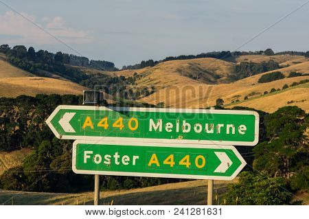 Signs On The South Gippsland Highway Pointing Towards Foster And Melbourne, Among The Rolling Hills 