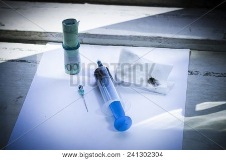 White Sheet Of Paper. It Has A Syringe With Solutions, A Needle, And Euro Money. Background Window I