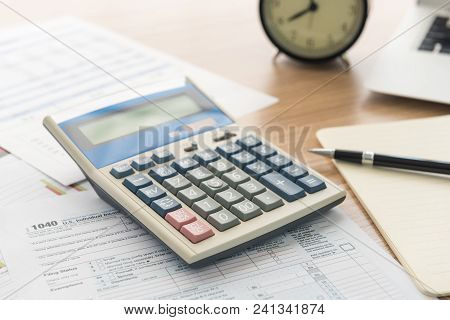 Calculator On The Desk With A Laptop And A Background Of Business.