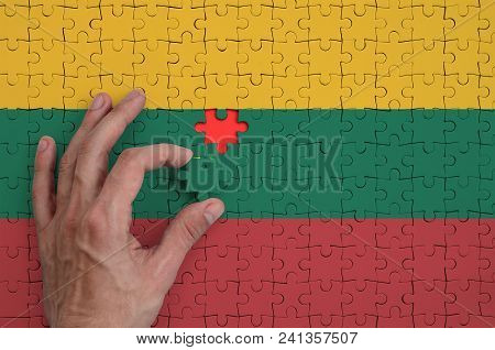Lithuania Flag  Is Depicted On A Puzzle, Which The Man's Hand Completes To Fold