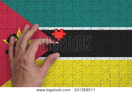 Mozambique Flag  Is Depicted On A Puzzle, Which The Man's Hand Completes To Fold