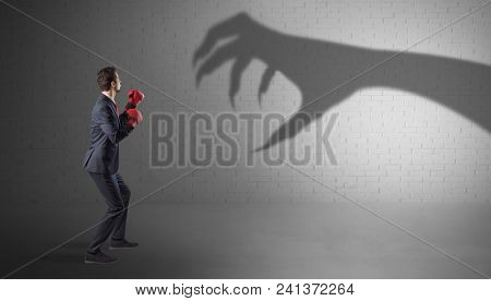 Tiny businessman fighting with scary hand shadow