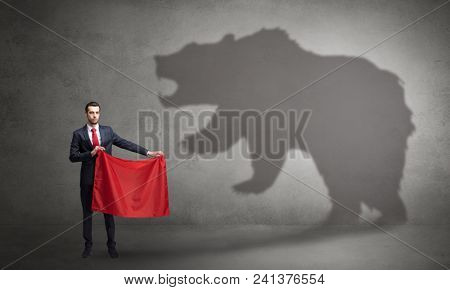 Businessman standing with red cloth in his hand and big bear shadow on his background