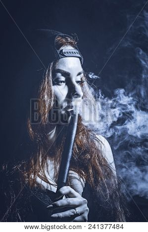 Red-haired Sexy Girl In A Cafe Dressed In Swimsuit And Cap Smoking A Hookah. Toned Image. Concept Of