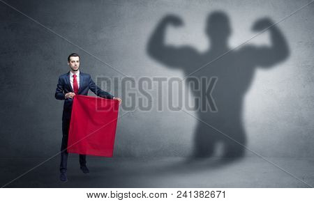 Businessman standing with red cloth on his hand and strong hero shadow on the background