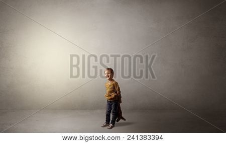 Little waggish kid staying alone in a big empty room with his plush