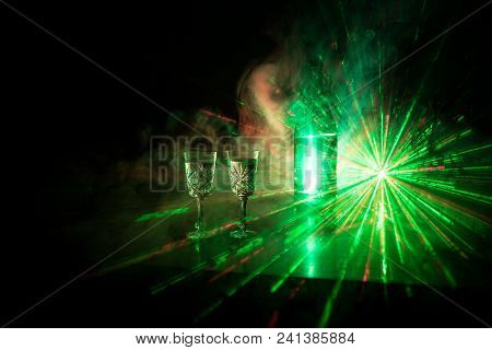 Two Glasses Of Vodka With Bottle On Dark Foggy Club Style Background With Glowing Lights (laser, Sto
