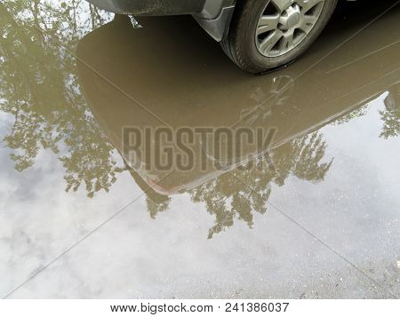 Car Wheel In A Puddle Of Water After Rain. Reflection In A Puddle, Rainy Weather