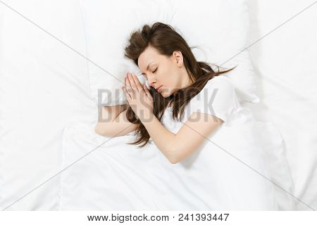 Top View Of Head Of Happy Brunette Young Woman Lying In Bed With White Sheet, Pillow, Blanket. Sleep
