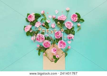 Creative Layout With Pink Tea Rose Flowers, Leaves Fly Out Of Croped Craft Paper Envelope In Shape O