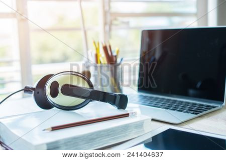 Student Learning Online Study Concept : Headphones On Books And Computer With Pens Box In Working Pl