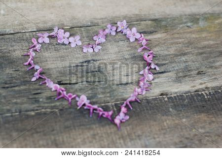 Spring Flowers. Lilac Flowers Frame Heart Shape Textured Rustic Gray Wooden Background.