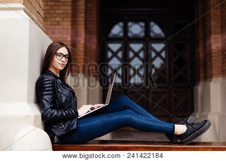 Smiling Student Girl Sitting On Bench In Park, Working With Laptop And Taking Notes, Preparing For E