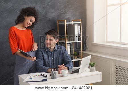 Cheerful Couple Of Young Colleagues Working In Modern Office. Two Coworkers Discussing Their Work, W
