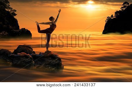 Yoga Woman Meditating In Nataradjasana Pose Standing On Stone Over Clouds Wave During Beautiful Sund