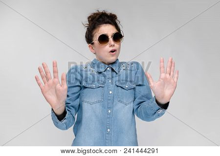 Young Girl In Black Cat Glasses On A Gray Background. Portrait Of A Young Beautiful Girl. Charming G